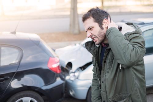 A man holding his neck in pain after being in a rear-end car accident.